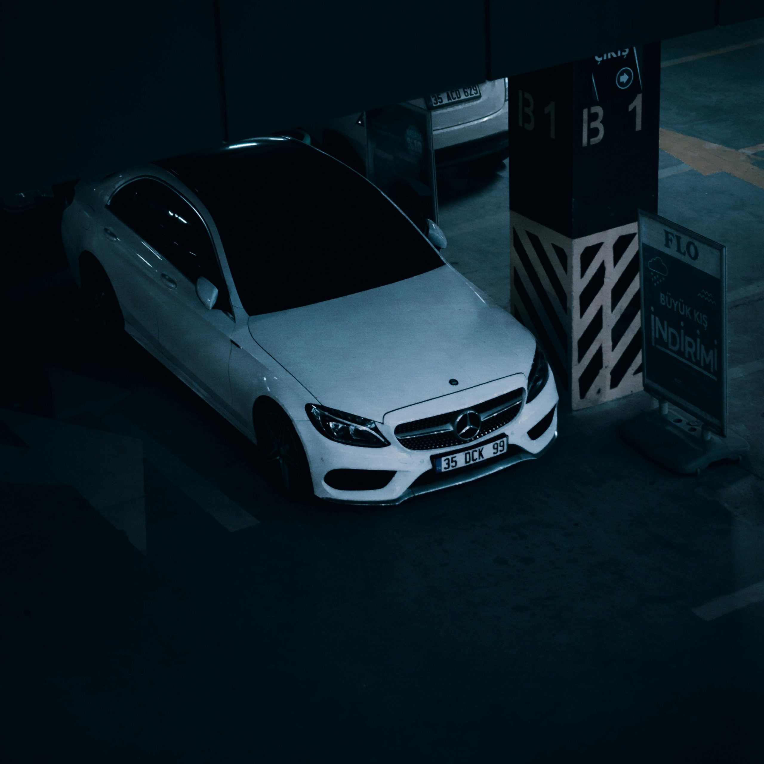 High angle shot of a white Mercedes Benz parked in an indoor parking garage.